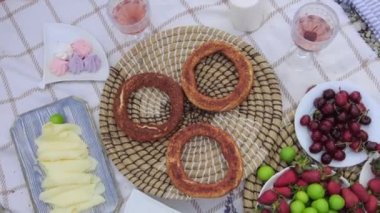 Various food at the picnic and women disassembling bagels from the stand. Mid shot