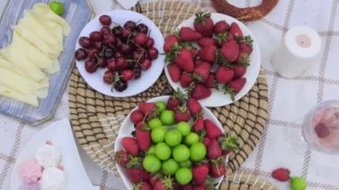 Women at a picnic disassemble taking fresh fruit from plates. Mid shot