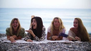 Beach picnic - four women lying on the blanket. Mid shot