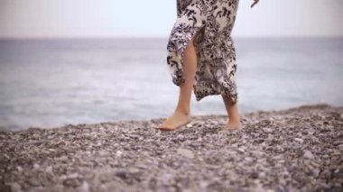 A woman running on the pebbles by the sea. Mid shot