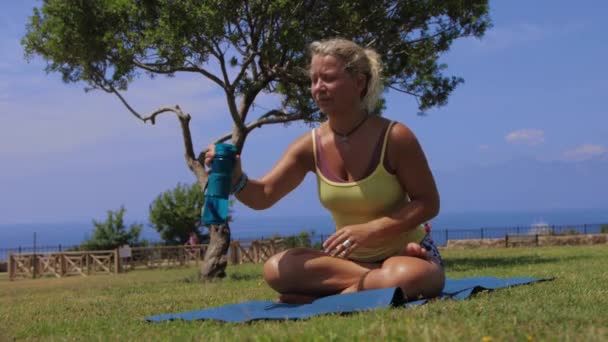 Adult Woman Doing Yoga Nature Sits Mat Drinking Water Plastic — Stock videók