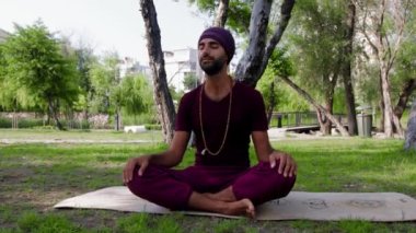 Arabian man doing yoga in the park. Mid shot