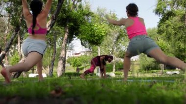 TURKEY, ANTALYA 07-06-2022: an arabian man doing yoga in the park with his female students. Mid shot