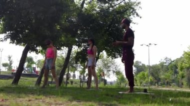 TURKEY, ANTALYA 07-06-2022: an arabian man runs a yoga practice for his female students in the green park. Mid shot
