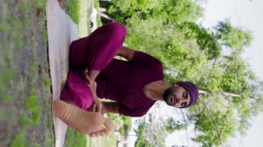 An arabian man running yoga class - teaches how to properly sit in the lotus position. Mid shot