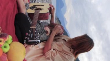 A woman with her little daughter spending time on picnic by the sea. Mid shot