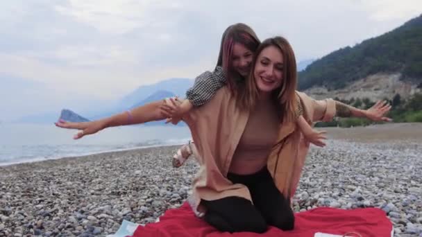 Lächelnde Mutter Reitet Ihre Tochter Auf Dem Rücken Meer Entlang — Stockvideo