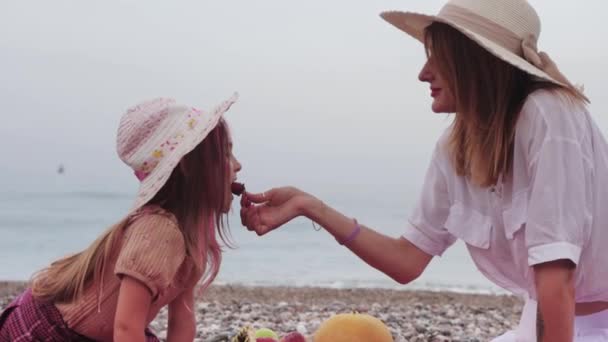 母亲的家人和她的小女儿坐在沙滩上的毛毯上吃草莓 — 图库视频影像