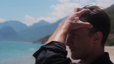 Çekici bir adam ıslak saçlarını parmaklarıyla arkaya tarar. Orta çekim