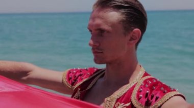 Deniz suyunda duran kırmızı manto tutan çekici bir dansçı. Orta çekim