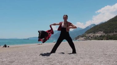 Sahne kostümlü çekici bir adam deniz kenarındaki performansını gösteriyor. Orta çekim