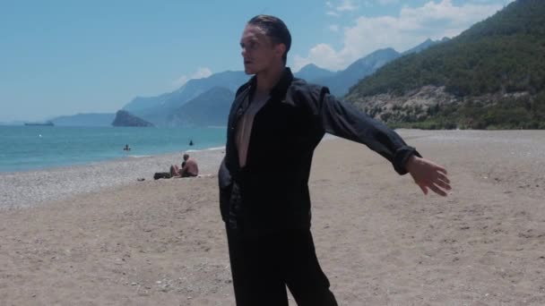 Seorang Pria Menarik Dalam Kemeja Hitam Menari Pantai Ditengah Tembakan — Stok Video