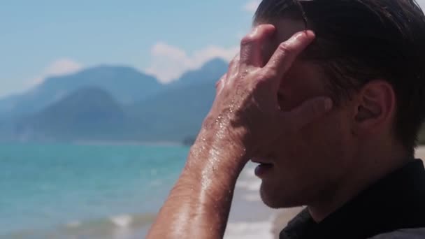 魅力的な男が戻って海でぬれた髪を結合します ミッドショット — ストック動画