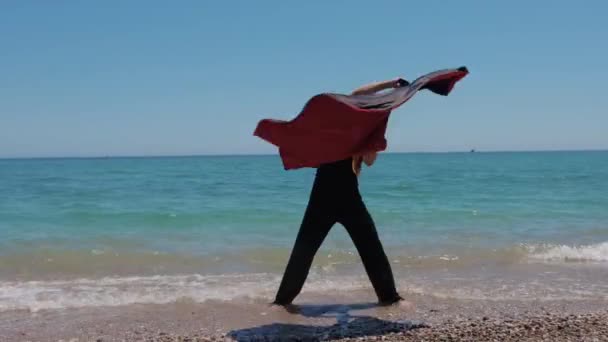 Aantrekkelijke Mannelijke Danser Zwaaiend Met Een Rode Mantel Aan Kust — Stockvideo
