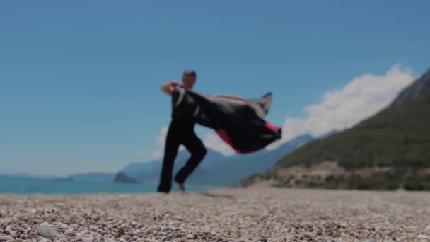 小石のビーチでのパフォーマンスを示す舞台衣装の魅力的な男 ミッドショット — ストック動画