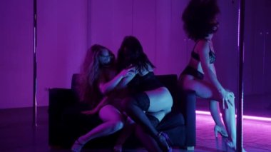 İç çamaşırlı üç seksi kadın özel odada gösteri yapıyor. Orta çekim