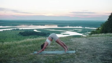 Yoga seansı açık havada. Yoga minderinde egzersiz yapan zayıf bir kadın. Orta çekim