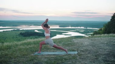 Yoga yapan bir kadın tepede yoga minderinde egzersiz yapıyor. Orta çekim