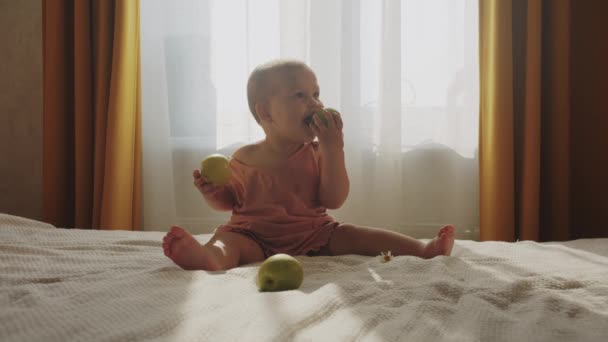 Bebé Juega Muerde Manzanas Verdes Sentadas Cama Mid Shot — Vídeo de stock