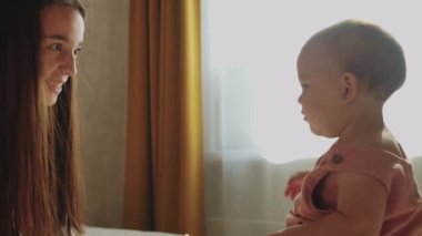 Anne ve küçük kızı. Annesi, kızın avucuna sprey tabancayla su sıçratıyor. Orta çekim