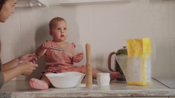 母親と赤ちゃんの娘の台所で一緒にかわいい料理 母親は娘の鼻に小麦粉を塗ります ミッドショット — ストック動画