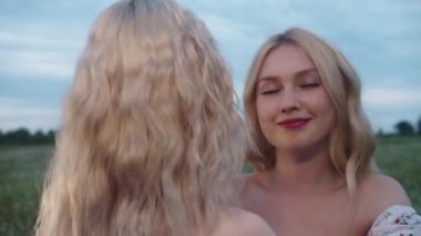 Sahada sarılan iki genç sarışın kadın. Orta çekim