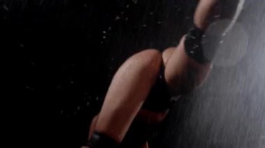 Two sexy young women dancing seductive dancing in the dark studio under the rain and shaking their ass. Mid shot