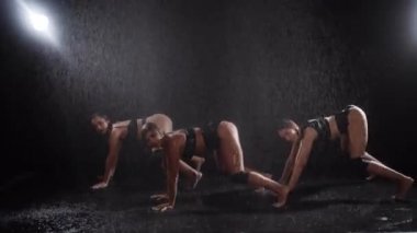 Three sexy women dancing and shaking their asses under the spray of water. Mid shot