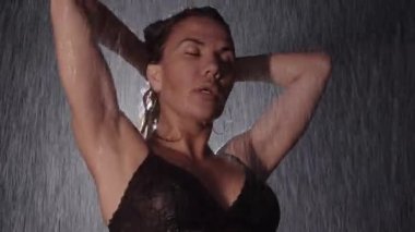 Yağmurun altında başını sallayan siyah iç çamaşırlı seksi kadın dansçı. Orta çekim