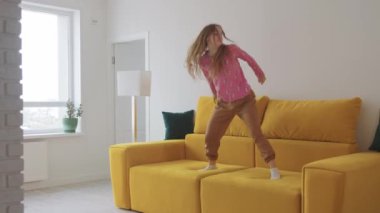 Sarı kanepede dans eden genç ve güzel bir kadın. Orta çekim