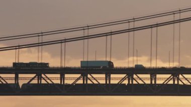 Ponte 25 de Abril Lizbon Portekiz - 25 Nisan Köprüsü, gün doğumunda köprüden geçen araba karınca izleri. sabah