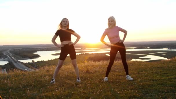 Две Молодые Спортивные Женщины Стоящие Поле Закате Согревающие Свое Тело — стоковое видео
