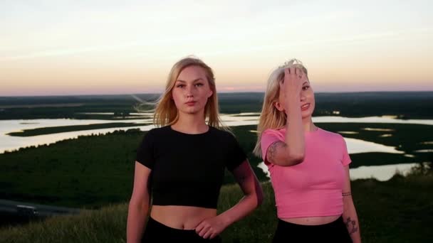 Dwie Młode Sportowe Blondynki Stojące Boisku Zachodzie Słońca Patrzące Kamerę — Wideo stockowe