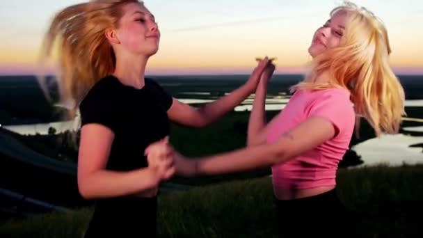 两名年轻而活泼的金发女子在日落时一起在田里跳舞 — 图库视频影像