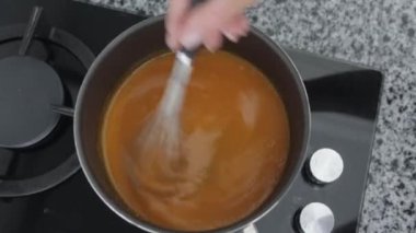 Bir kadın tencerede tuzlu karamel eritiyor. Orta çekim