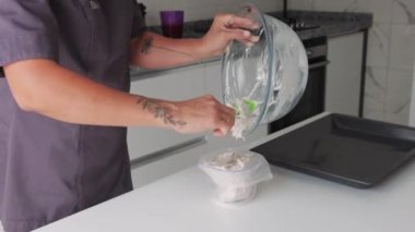 Bir kadın mutfaktaki pasta poşetine krema koyar. Orta çekim