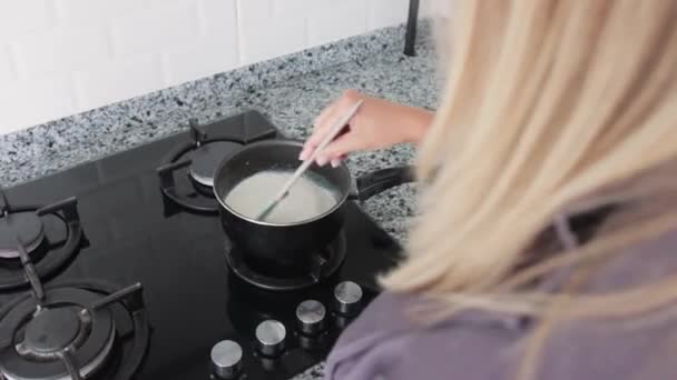 Femeia Blondă Încălzește Laptele Într Cratiță Sobă Mid Shot — Videoclip de stoc