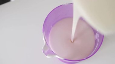 Cam ölçü kabındaki pasta için vanilya kremi döküyorum. Orta çekim