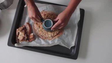 Kadın bir pasta şefi bademli pastanın ortasından yuvarlak bir parça kesiyor. Orta çekim