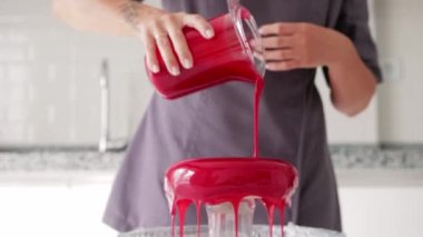 Kadın bir pasta şefi mutfaktaki pastanın üstüne kırmızı şarap döker. Orta çekim