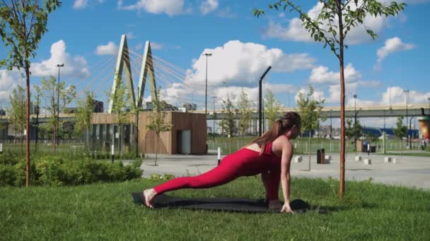 Μια Ενήλικη Γυναίκα Κόκκινη Στολή Κάνει Ασκήσεις Τεντώματος Στο Πάρκο — Αρχείο Βίντεο