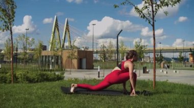 An adult woman with nice body and thick ass doing sports exercises in the park. Mid shot