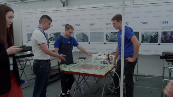ロシア Kazan 航空技術展示会でテーブルの上に立つ若い人たち ミッドショット — ストック動画