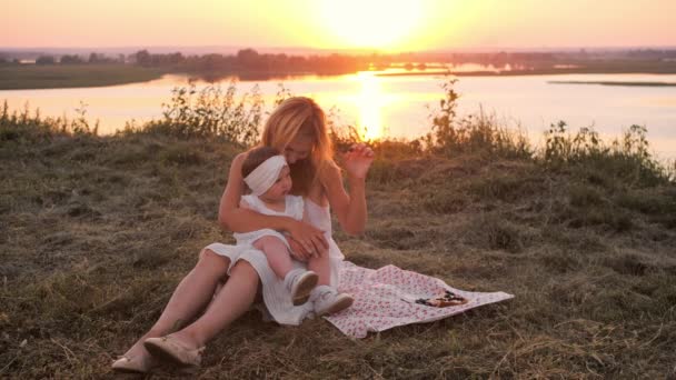 Жінка Сидить Ковдрі Своєю Донькою Пагорбі Заході Сонця Їсть Ягоди — стокове відео