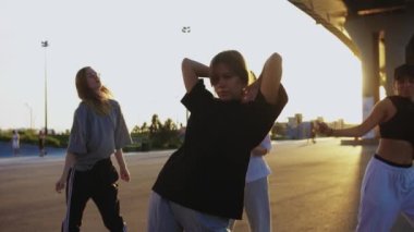 Gün batımında köprünün altında dans eden dört genç kadın. Orta çekim