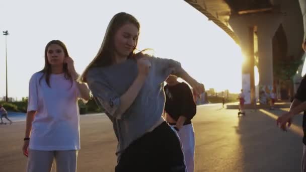 早い日没で橋の下で4人の若い笑顔の女性のフリースタイルダンス ミッドショット — ストック動画