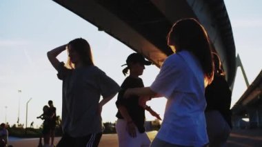 Gün batımında köprünün altında hip hop dansı yapan dört sıska genç kadından oluşan bir grup. Orta çekim