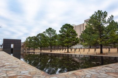 Oklahoma City, Oklahoma, United States of America - January 18, 2017. Oklahoma City National Memorial in Oklahoma City, OK, with Reflecting Pool, the Gates of Time and vegetation. clipart