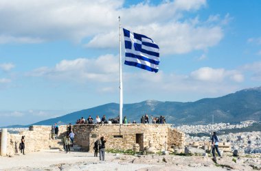 Atina, Yunanistan - 17 Kasım 2016. Yunanistan 'ın Yunanistan' daki Akropolis harabeleri üzerine ulusal bayrak, halkla birlikte.