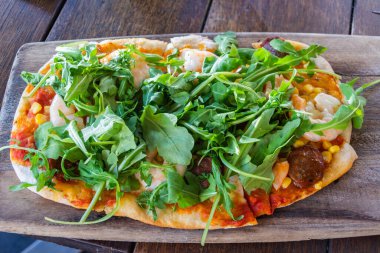 Sarımsaklı karides ve sucuklu pizza, manchego peyniri, sofrito, karamelli soğan, kapsika, safran, maydanoz.